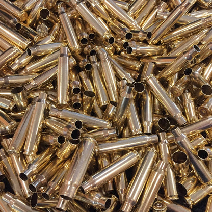 Frame-filling pile of bright yellow polished .223 brass cartridges showing open mouths and spent primer bases.