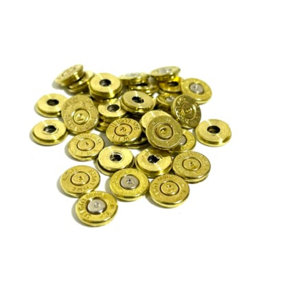 A scattered pile of multiple polished brass 9mm Luger bullet slices showing various spent primers.