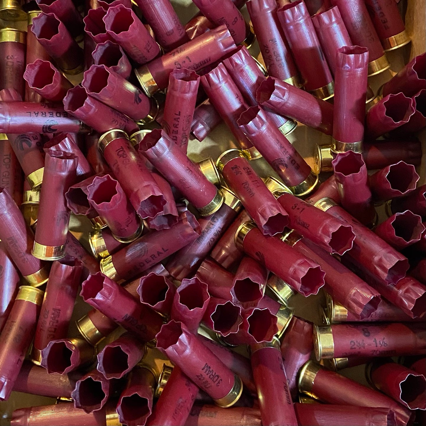 A bulk pile of dark red Federal 12 gauge spent casings, loose-packed for crafting.

