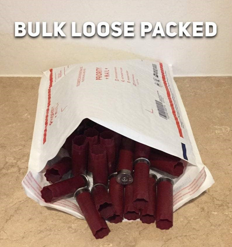 Dark red empty 12 gauge shotgun hulls spilling out of a Priority Mail envelope with BULK LOOSE PACKED text overlay.