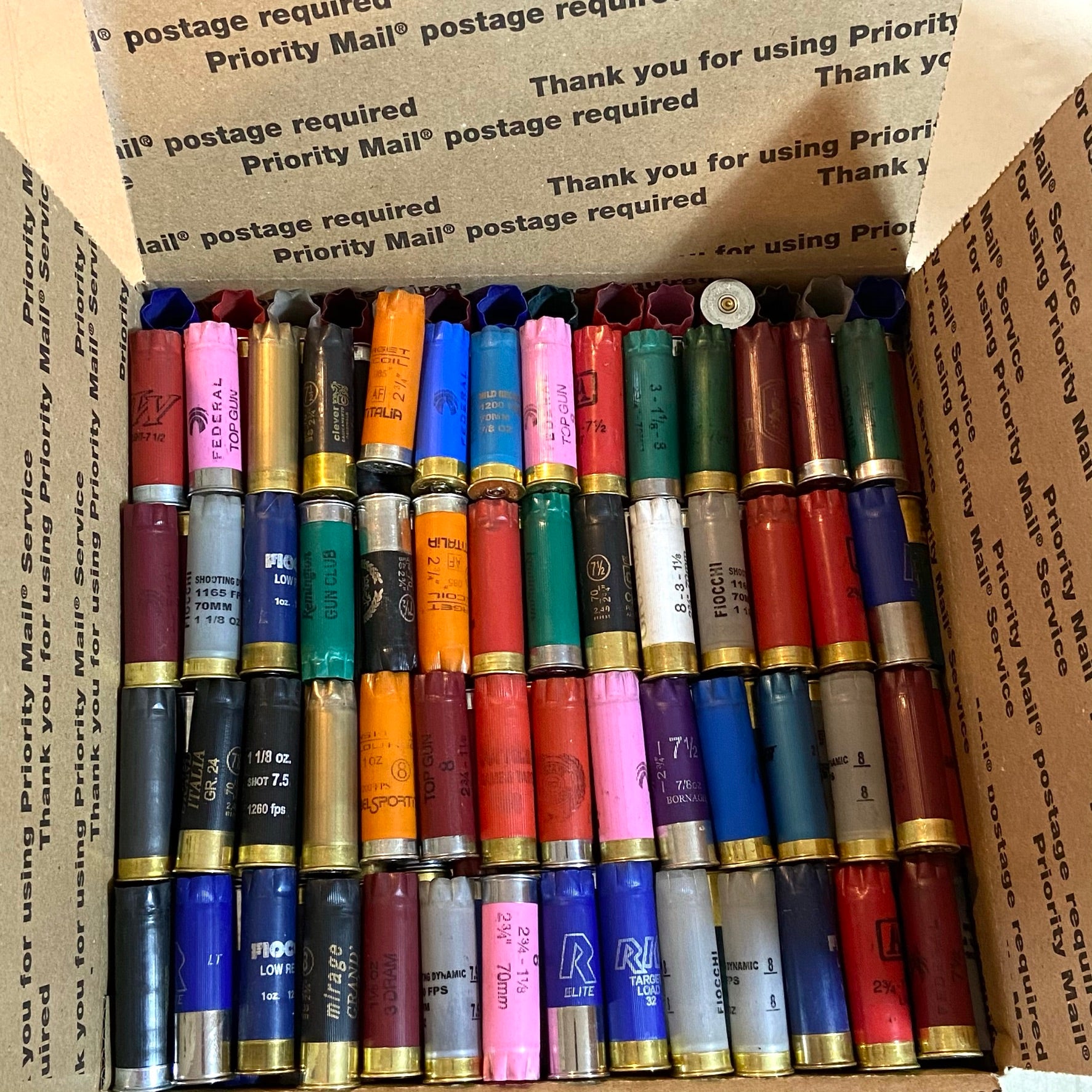 Rows of multi-colored 12ga shells in a box. Inert 12ga shells for crafts (no powder/primers).
