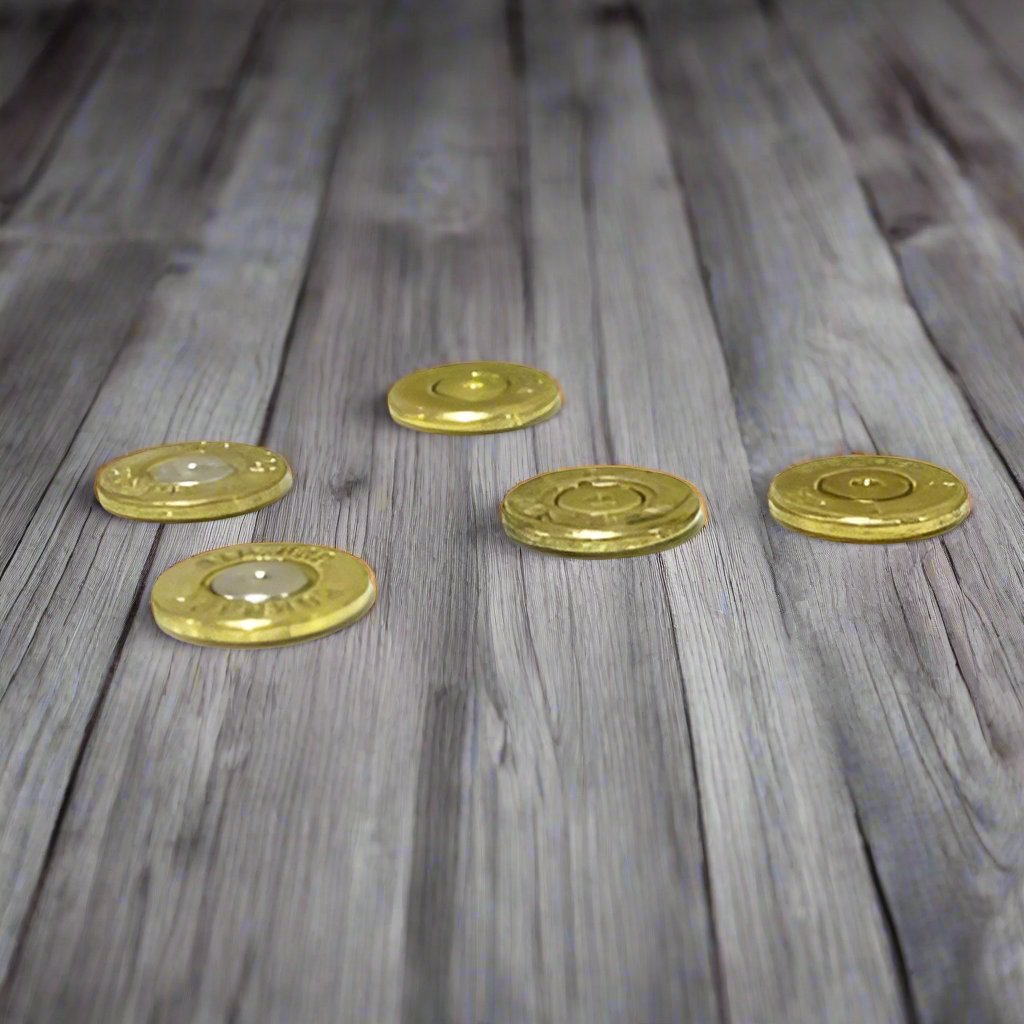 Five thin brass bullet slices scattered on a weathered wood plank, showing thin edge profiles