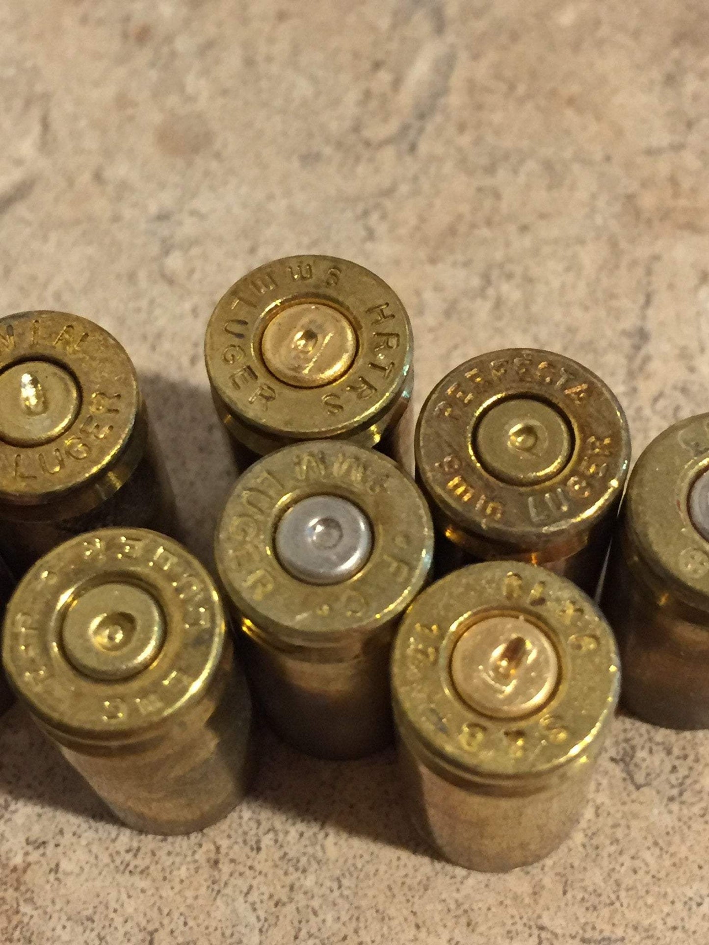Headstamps facing up on several brass casings, showing mixed silver and gold-colored primers