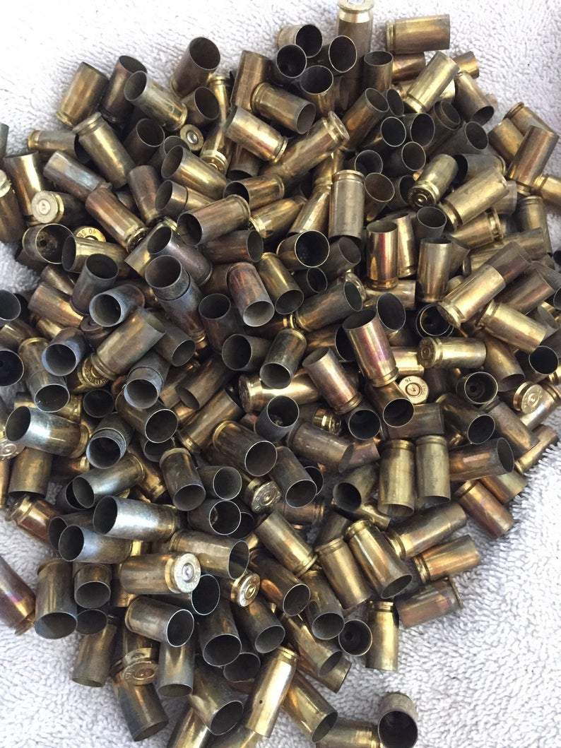 Large loose pile of brass casings scattered across a white fabric surface