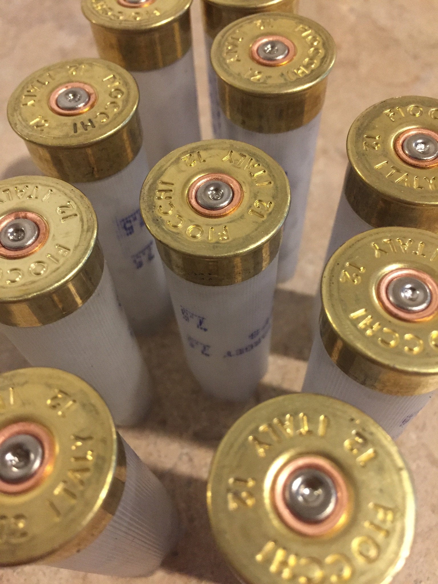 9 brass heads of translucent Fiocchi 12 gauge shotgun shells viewed from above showing headstamp text