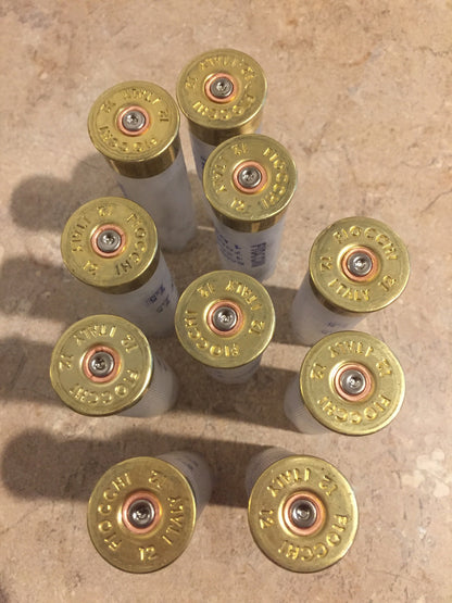9 brass heads of translucent Fiocchi 12 gauge shotgun shells viewed from above showing headstamp text