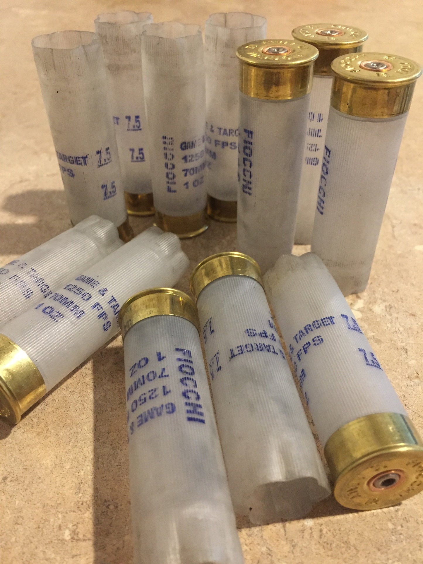10 translucent white Fiocchi 12 gauge shotgun shells clustered together on a stone surface