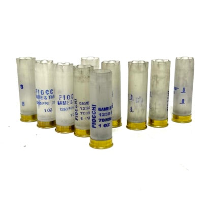 9 translucent white Fiocchi 12 gauge shotgun shells with brass heads standing on a white background