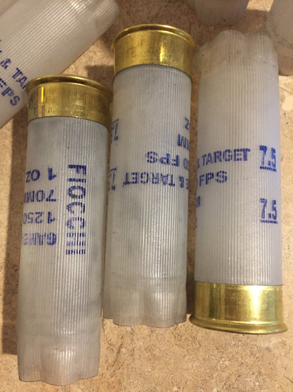 3 translucent white Fiocchi 12 gauge shotgun shells lying together showing Fiocchi and Target headstamp text