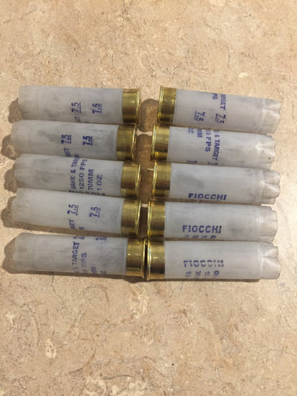 10 translucent white Fiocchi 12 gauge shotgun shells lying in a row with brass heads and open mouths