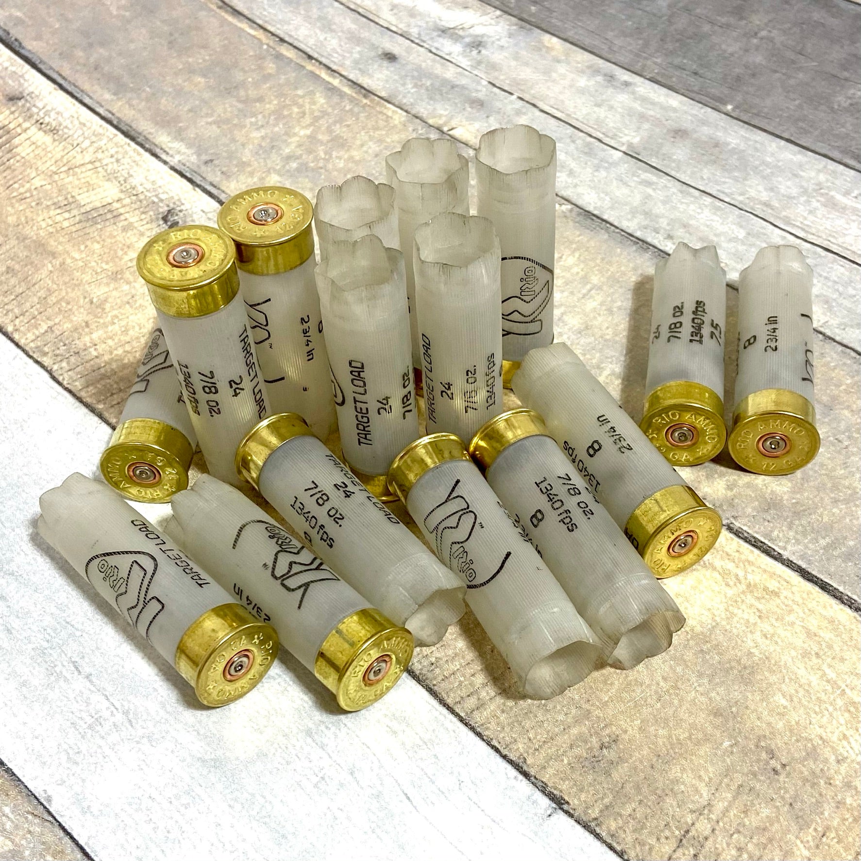 A pile of empty clear translucent 12 gauge Rio shotshells lying on a rustic wooden surface for christmas lights.
