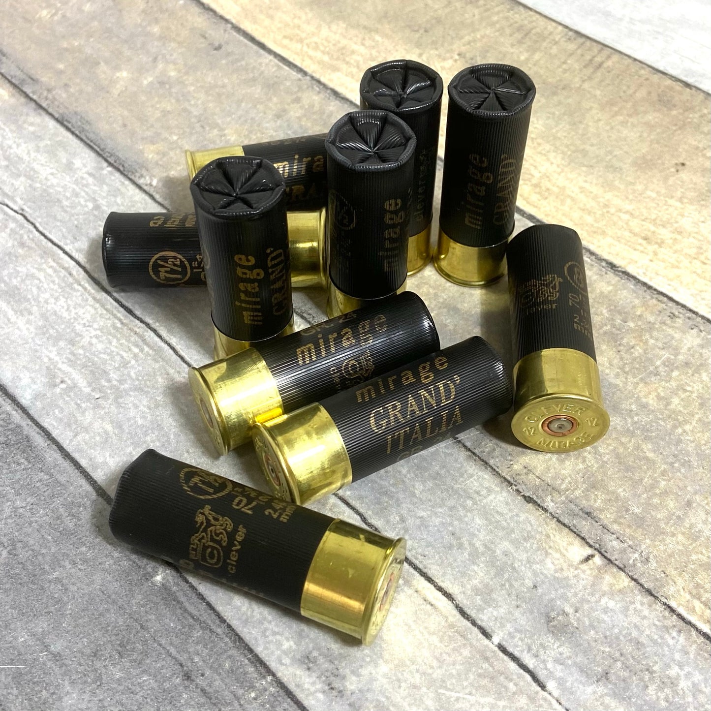 Clever black dummy rounds with shiny brass bases arranged on a light gray wooden surface.