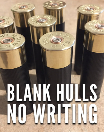 Seven black 12-gauge shotgun hulls with brass heads and no markings, clustered upright