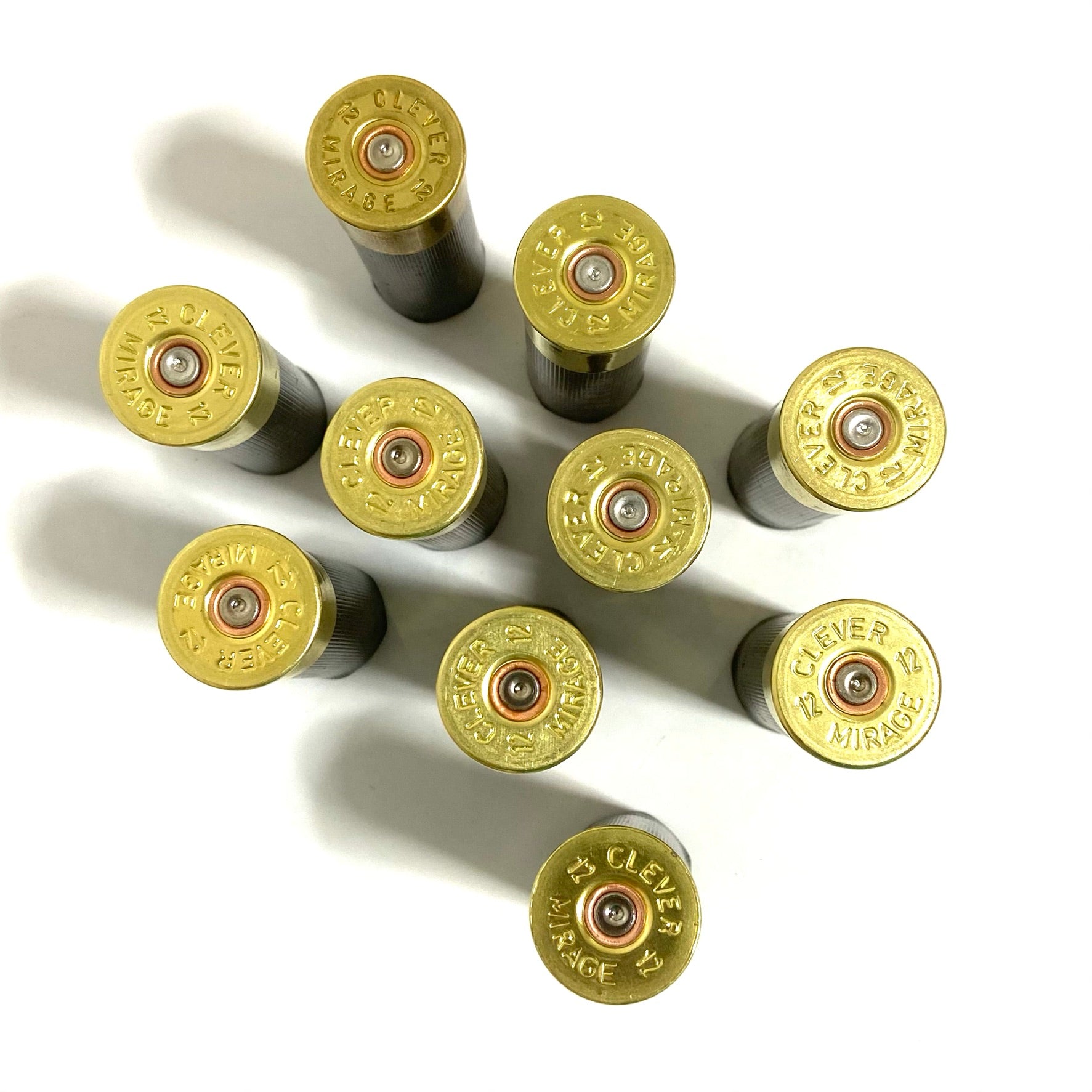 Top-down view of black spent hulls with detailed gold brass markings, spent primers arranged on a white background.