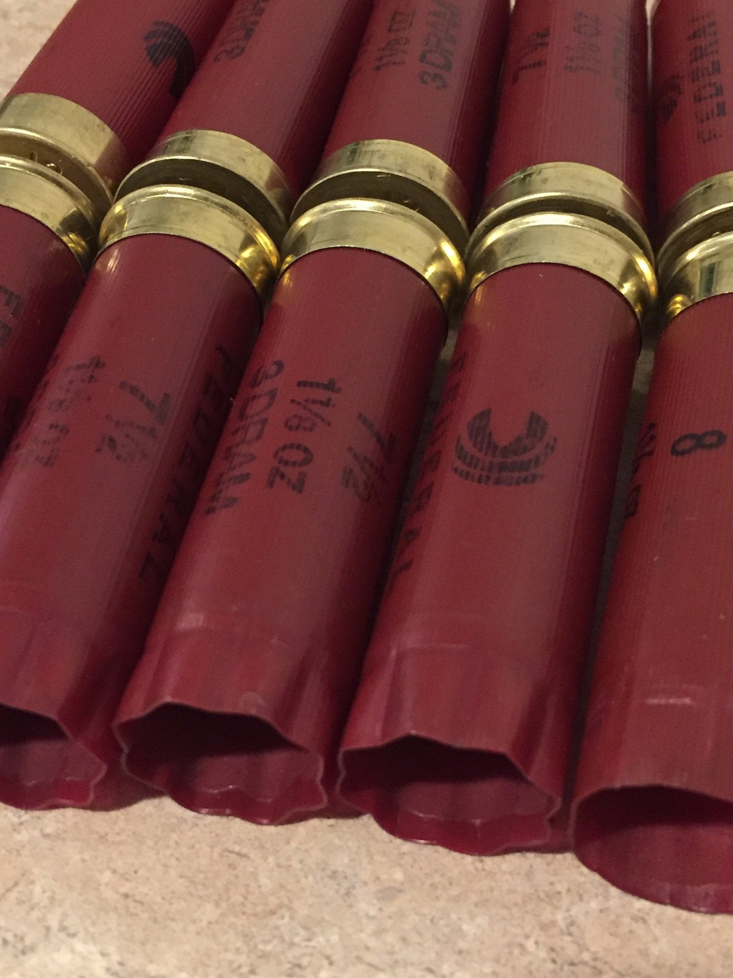Close-up of the star-crimped ends of several red shotgun shells arranged vertically.