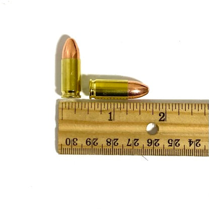 9mm dummy rounds placed against a wooden ruler for scale for cosplay props and bullet jewelry supplies.
