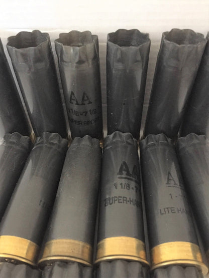 Ten charcoal gray Winchester AA spent shells standing upright in a staggered group on a white surface, showing brass bases.