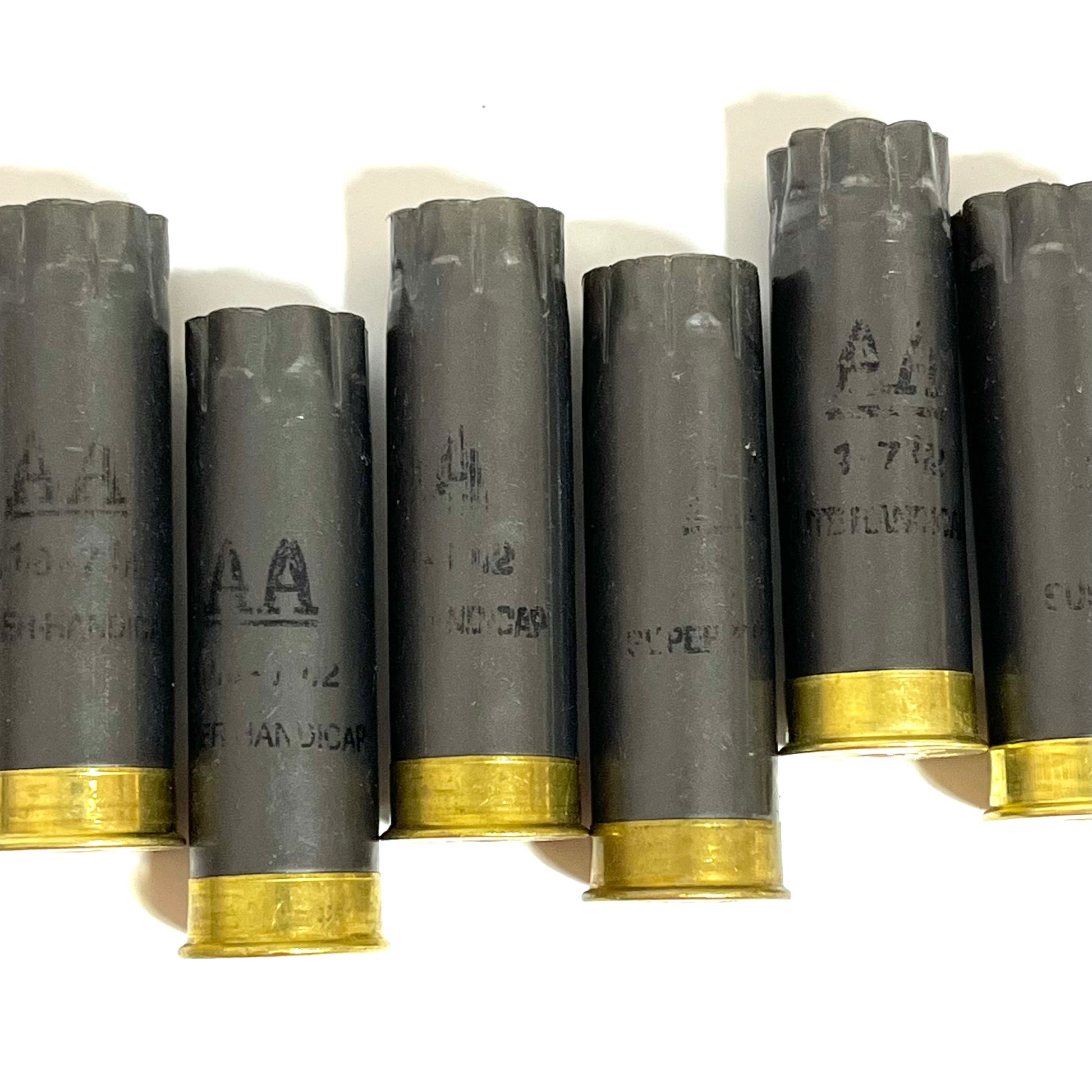 Five dark gray Winchester AA spent shells standing upright in a single row on a white surface, with brass bases visible.