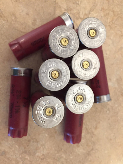 An assortment of authentic, once-fired dark red Federal 12-gauge empty shotgun shells showing both side views and silver headstamps. These recovered casings are perfect for detailed rustic DIY crafting projects.