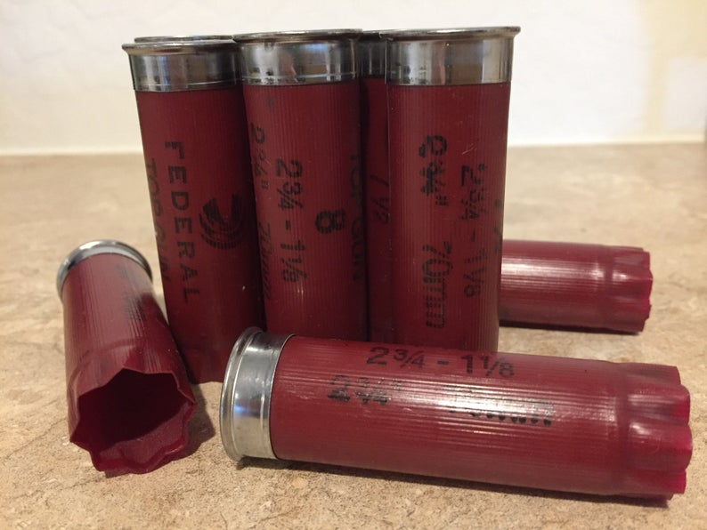 A small group of authentic, once-fired dark red Federal 12-gauge empty shotgun shells showing clear silver bases and black printed text. These recovered casings are ideal for detailed rustic DIY crafting projects.
