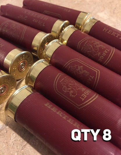Eight burgundy Herter’s Target 12 gauge shotgun shells lying diagonally on a stone countertop, with ‘QTY 8’ text overlay