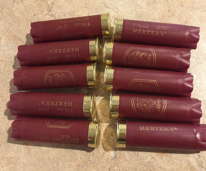 Ten burgundy Herter’s Target 12 gauge shotgun shells arranged in two rows on a stone countertop