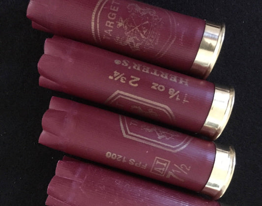 Closeup of stacked burgundy Herter’s Target 12 gauge shotgun shells on a black background, showing printed ‘Target’ and ‘7 1/2 FPS 1200’ markings