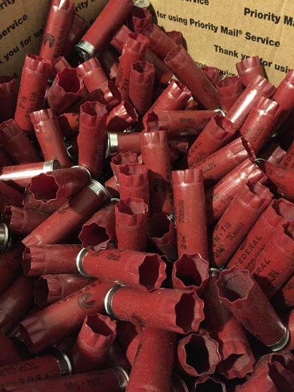 Large pile of empty dark red Federal shotgun hulls with open crimps piled in a padded Priority Mail shipping box.