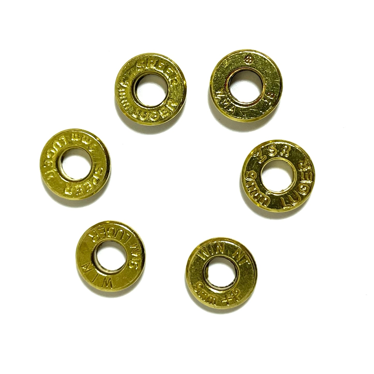 Six 9mm brass slices with primers removed arranged loosely in a ring, each stamped differently.