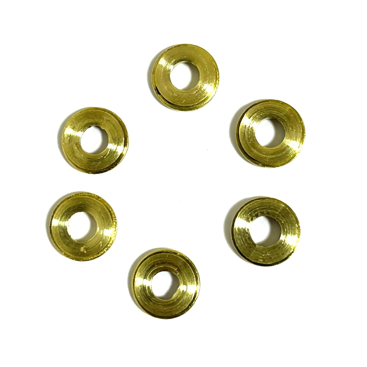 Six deprimed 9mm slices with hollow centers, backsides facing up, clustered together in a tight formation.