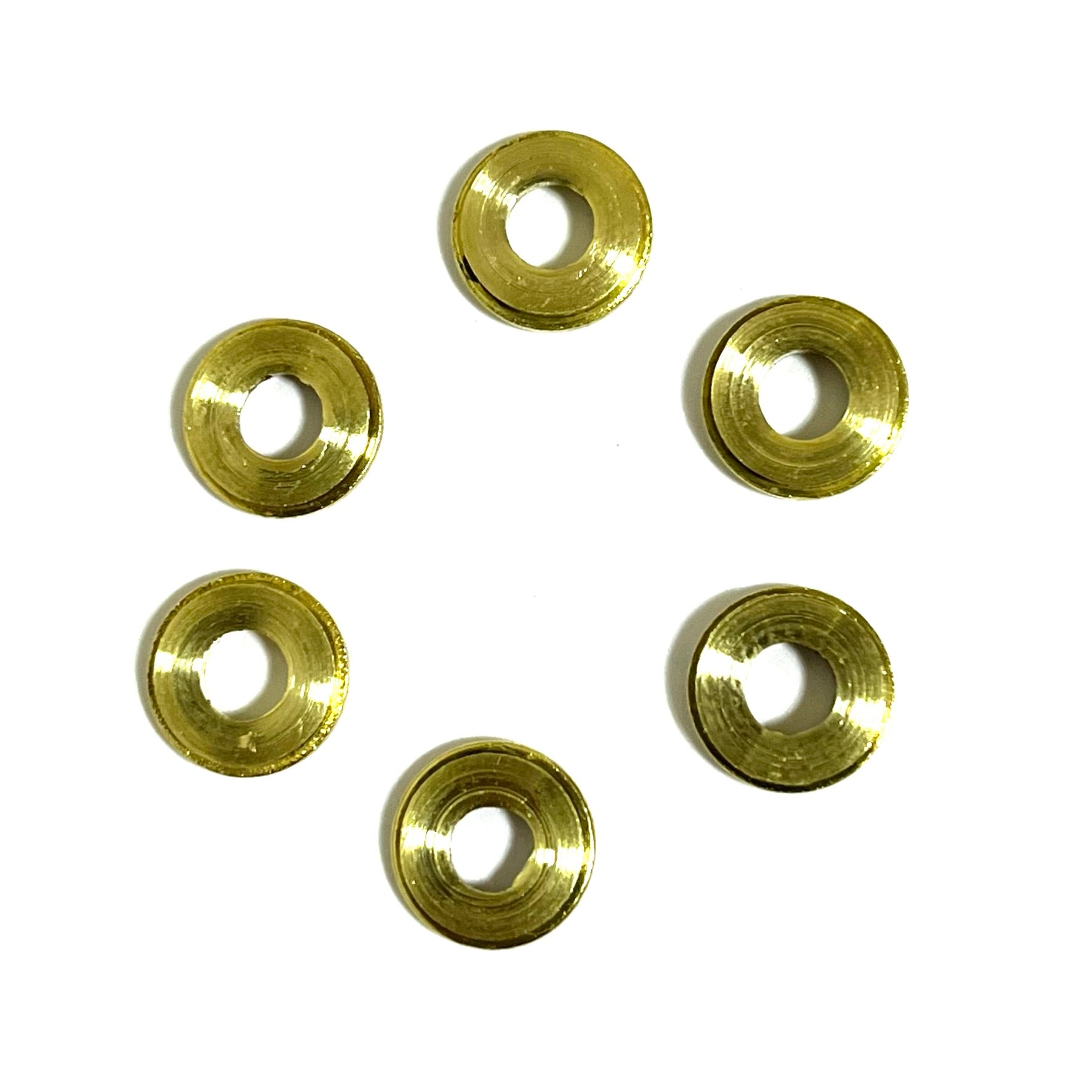 Six deprimed 9mm slices with hollow centers, backsides facing up, clustered together in a tight formation.