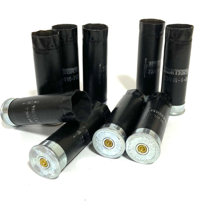 Seven black Herters 12 gauge shotgun shells with silver bases standing and lying on white background