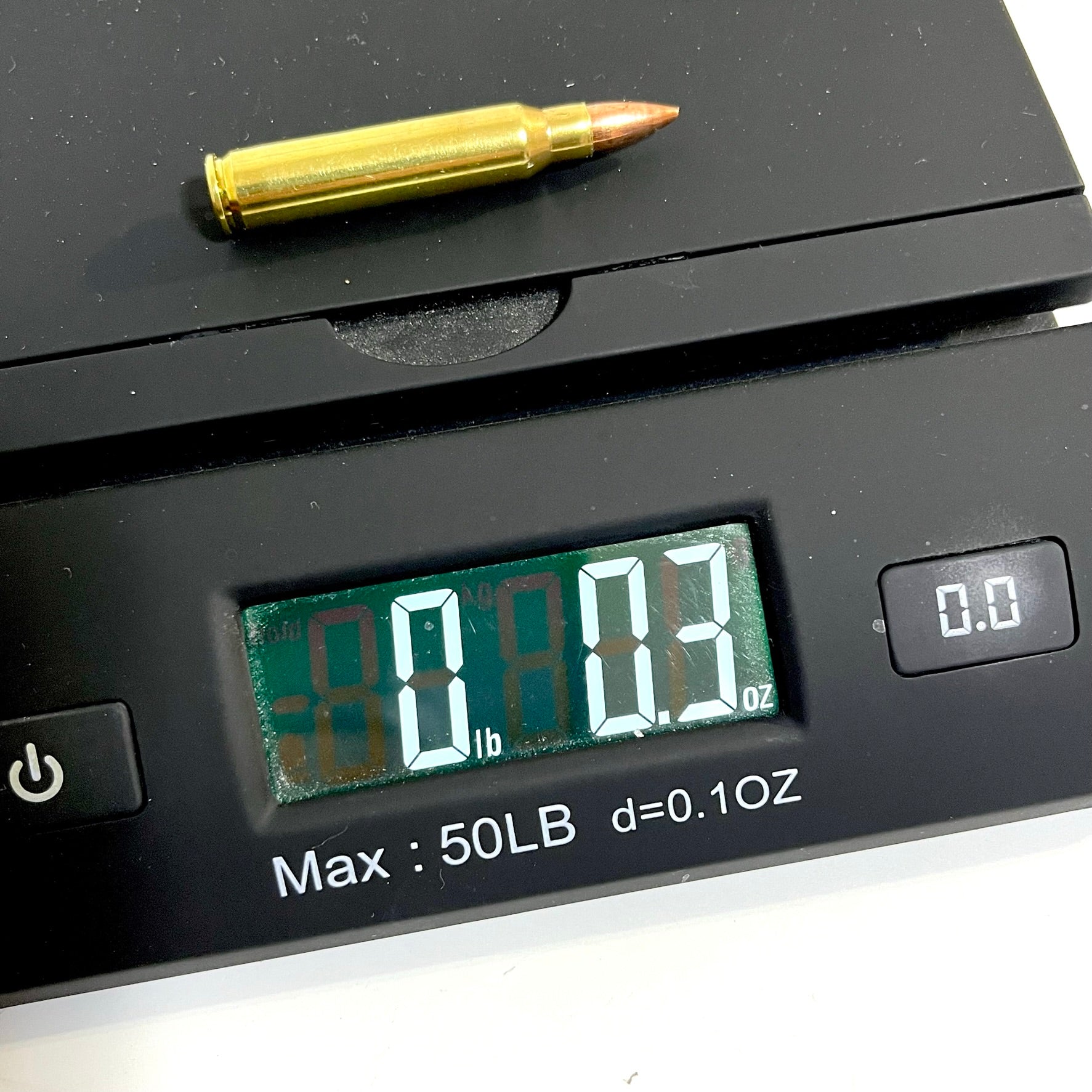 A single brass dummy cartridge placed on a digital scale, showing a weight reading of 0.3 oz.