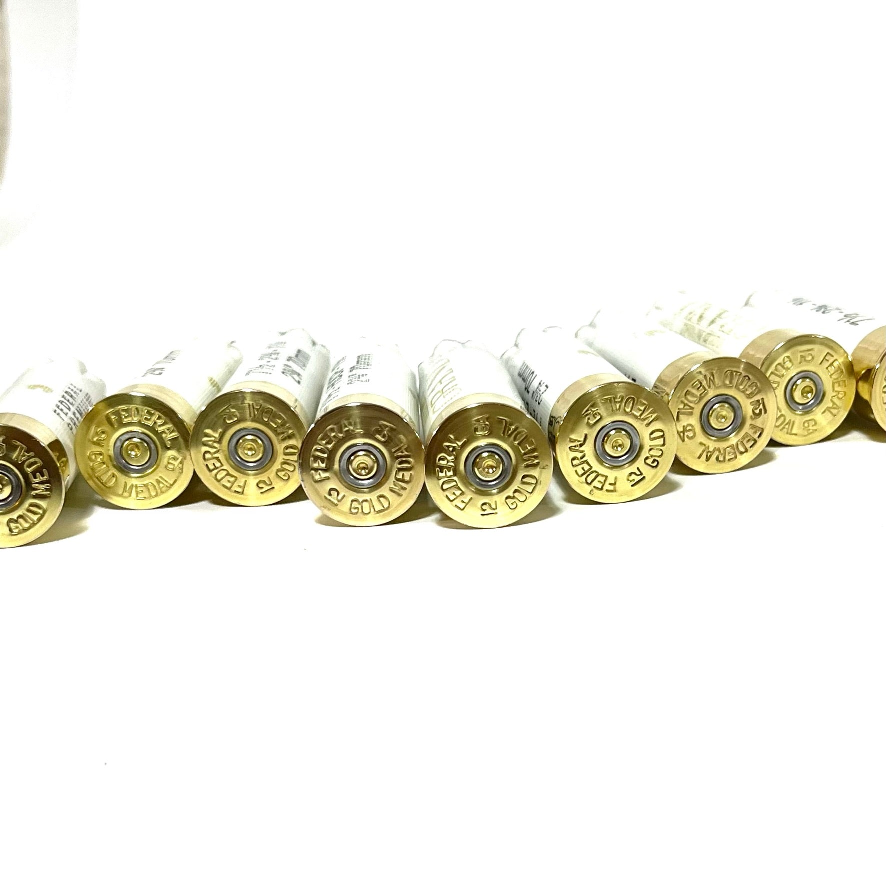 A row of white empty shotgun shells with gold bottoms arranged side-by-side against a white background.