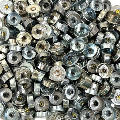 Silver 12 gauge shotgun shell end caps packed together, some showing stamped faces and others interiors.