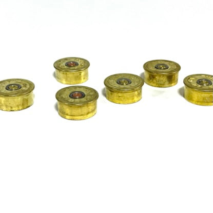 6 gold brass 12 gauge Federal shotgun shell headstamp bottoms lying on their sides on a white background