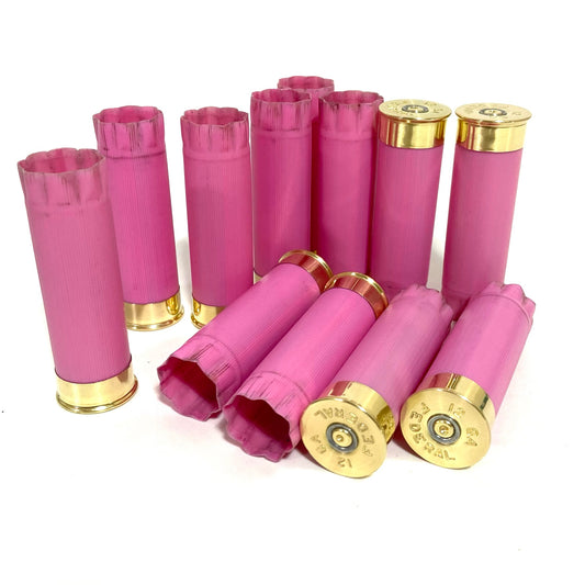 Twelve once-fired pink 12-gauge Federal shotgun hulls piled together, with several headstamps visible.