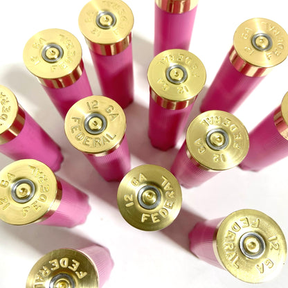 Several spent pink 12-gauge Federal shotshells fan outward, their brass headstamps reading '12 GA FEDERAL' clearly visible.