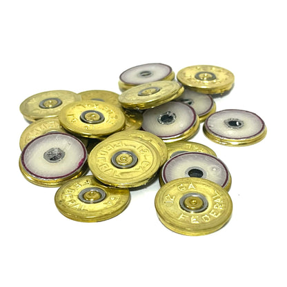 Round brass 12 gauge Federal headstamp slices with white enamel-lined centers on a white background
