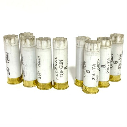 Eight used white Federal Top Gun 12ga shells with crimped tops, standing in two rows