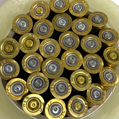 Cluster of gold high brass bases with silver primers viewed from above in a round container