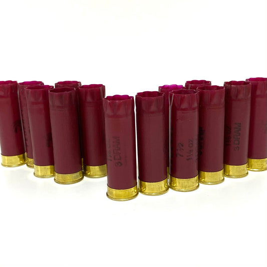 A neat row of empty dark red Federal twelve gauge shotgun hulls standing upright on a clean white background.