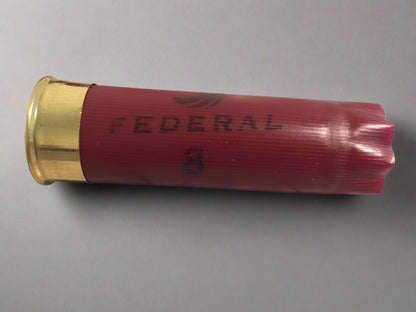 Close-up of a dark red spent cartridge with a brass base showing the Federal logo on the side.