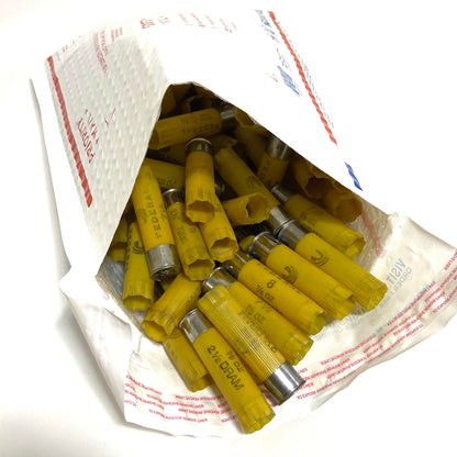 Bulk spent yellow 20 gauge shotgun shells packed inside an open white USPS Priority Mail padded envelope.