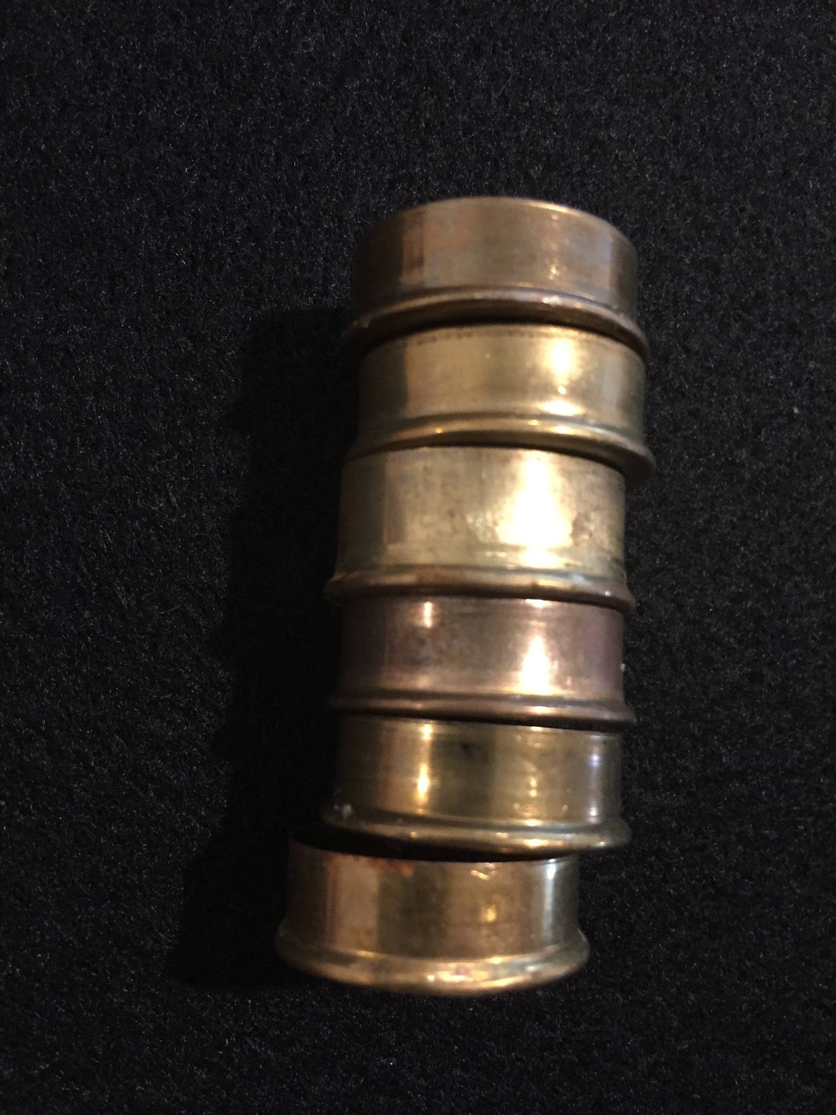 Stack of gold brass end caps viewed from the side on a black surface