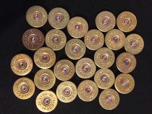24 gold brass Fiocchi 12 gauge headstamps arranged in rows on a black surface