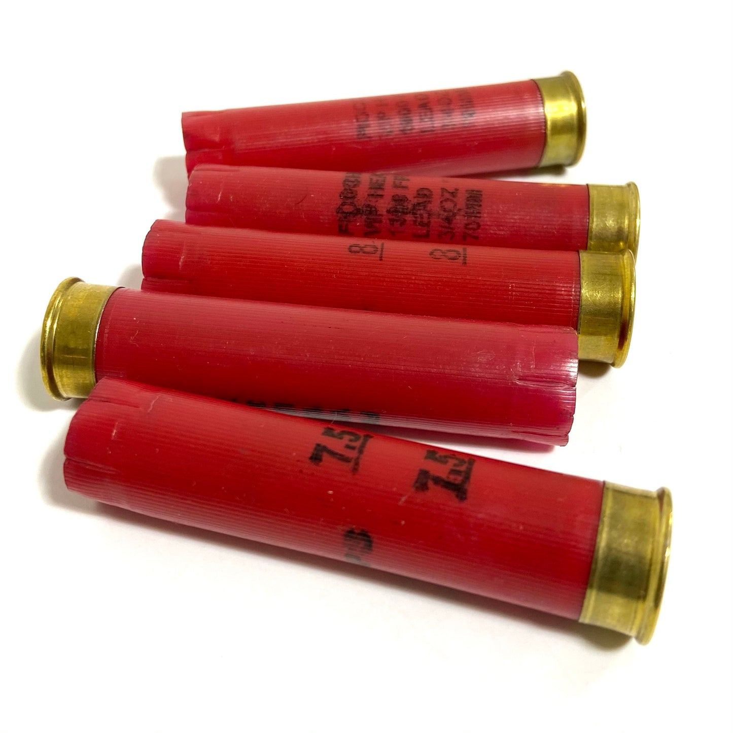 Five red Fiocchi 28 gauge shotgun shell hulls lying at an angle showing hull markings and open crimps