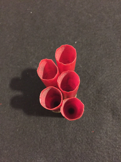 Overhead view of five open red Fiocchi 28 gauge shotgun shell hull mouths on a dark background