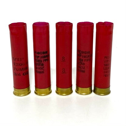 Five empty red Fiocchi 28 gauge shotgun shell hulls standing upright in a row