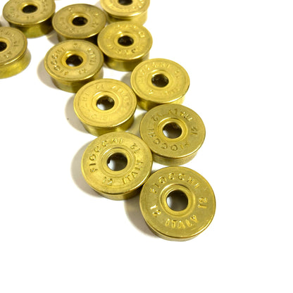 Gold Fiocchi 12 gauge deprimed shell bottoms piled together in a diagonal cluster, showing stamped markings.